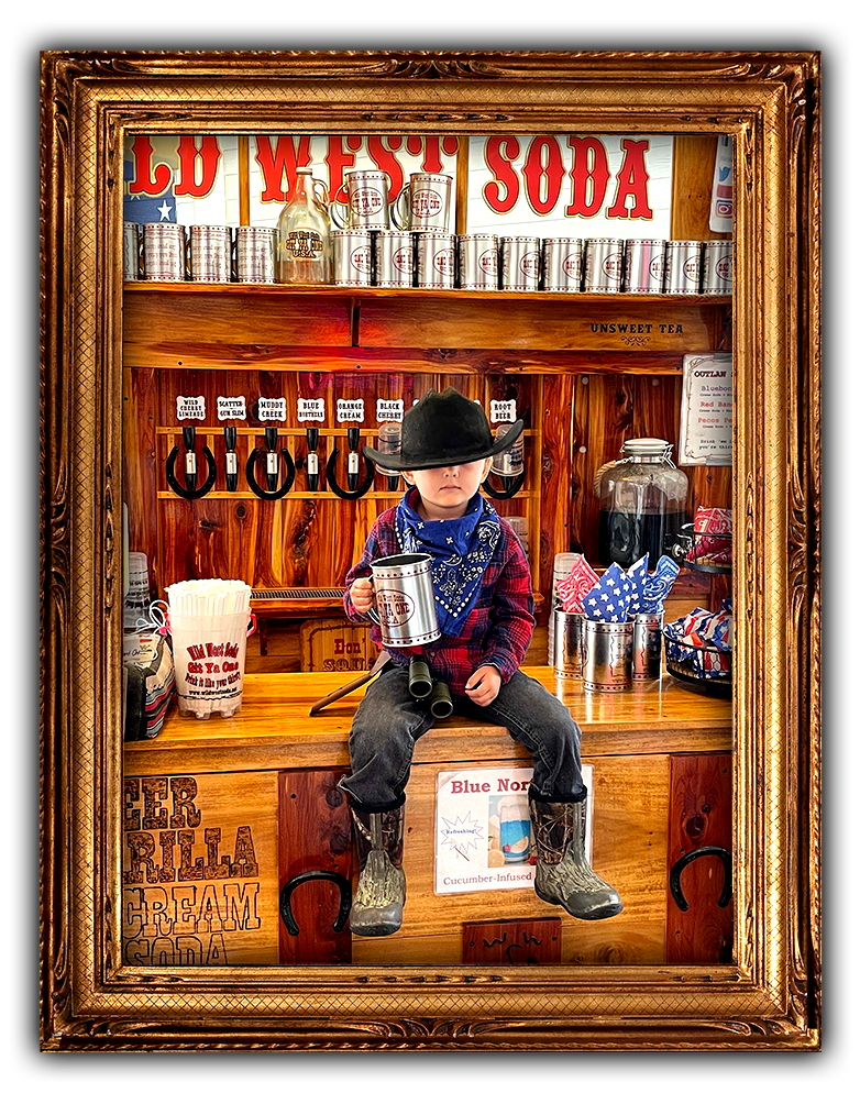 Young bow dressed up in cowboy attire sitting on the Wild West Soda counter